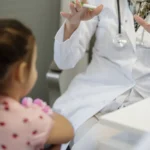 Pediatra revisando a un niño en consulta, imagen ilustrativa del seguro de salud para niños