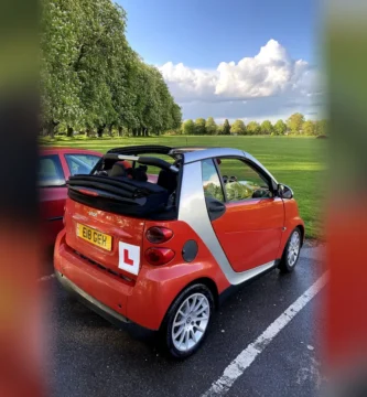 Coche de aprendizaje con placa L de conductor novel aparcado en un parque