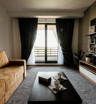 Salón de una vivienda con sofá, mesa de centro y ventanales