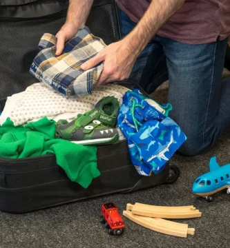 Padre preparando la mochila de su hijo antes de un viaje familiar