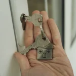 Mano sosteniendo un manojo de llaves junto a la cerradura de una puerta