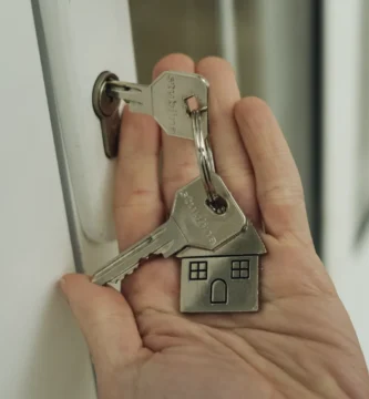 Mano sosteniendo un manojo de llaves junto a la cerradura de una puerta