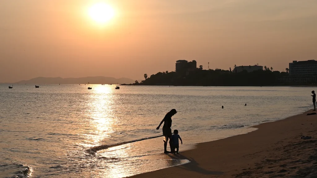 Padre e hijo paseando por la orilla del mar al atardecer, imagen ilustrativa de un seguro de vida familiar
