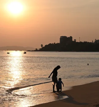 Padre e hijo paseando por la orilla del mar al atardecer, imagen ilustrativa de un seguro de vida familiar