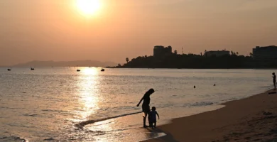 Padre e hijo paseando por la orilla del mar al atardecer, imagen ilustrativa de un seguro de vida familiar